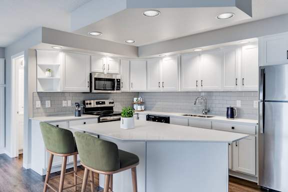 A modern kitchen with white cabinets, white backsplash, and a large island.