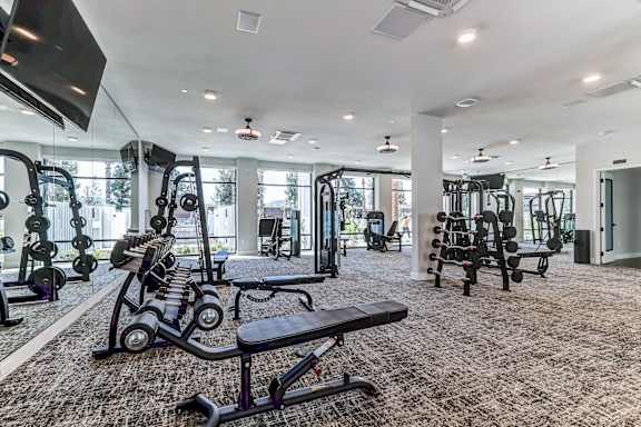A spacious gym with a variety of equipment and a flat screen TV mounted on the wall.