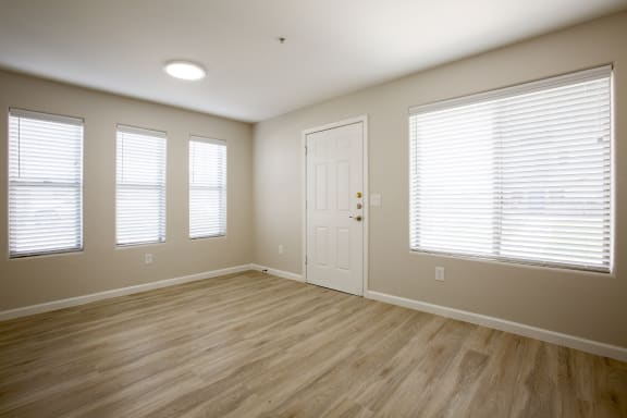 an empty bedroom with a door and three windows