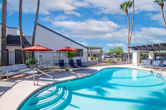 a pool with lounge chairs and umbrellas at the enclave at woodbridge apartments in sugar
