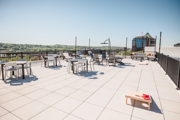 a rooftop patio with tables and chairs and a building in the background