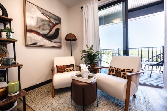 a living room with two white chairs and a balcony