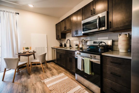 a kitchen with wooden cabinets and stainless steel appliances and a table with chairs