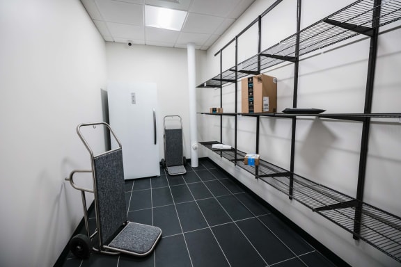 a room with a shelf with boxes and a refrigerator
