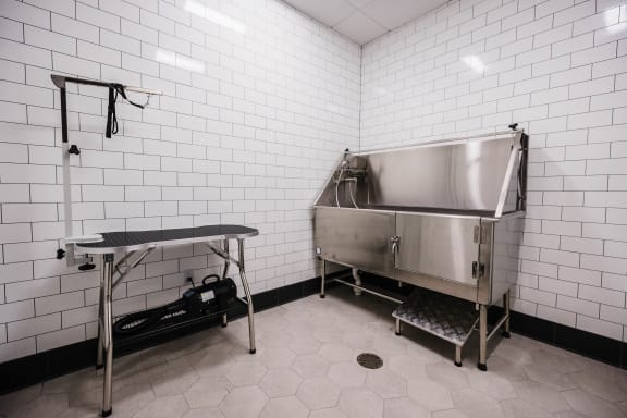 a large stainless steel sink in a room with white tiled walls