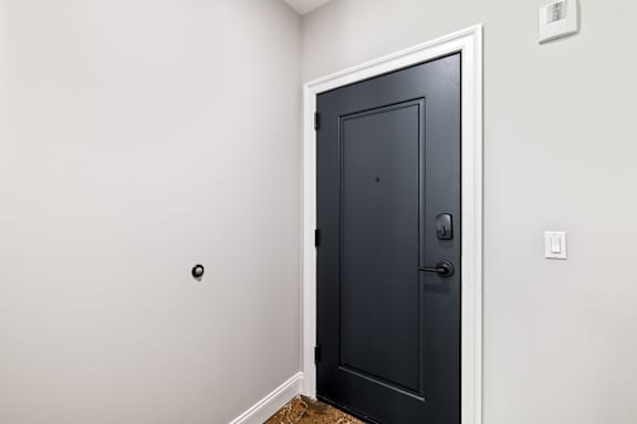 A black door with a silver handle is in a room with white walls.