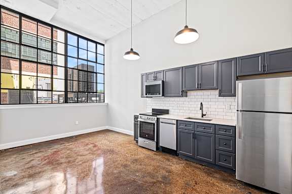 A kitchen with black cabinets and a stainless steel refrigerator.