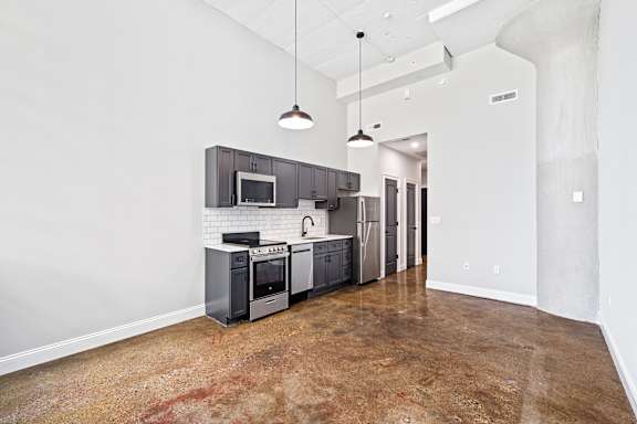 A kitchen with a refrigerator, microwave, oven, and sink.