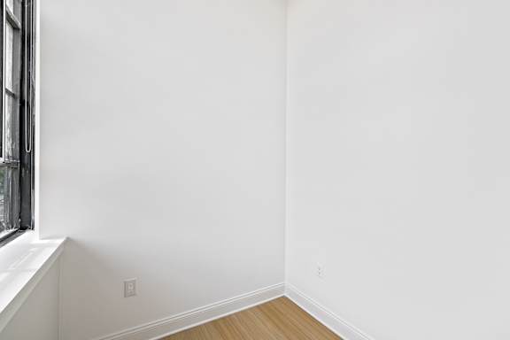 A white wall with a window on the left side.