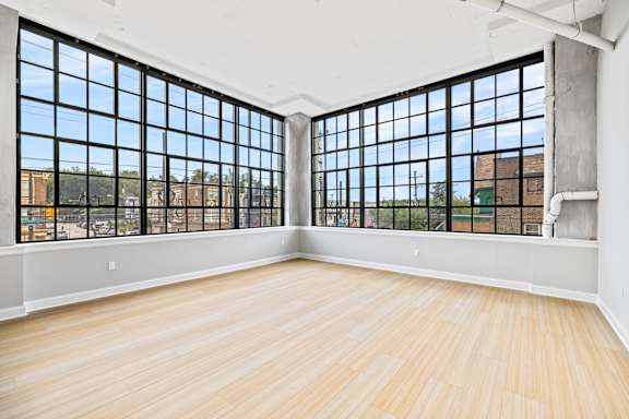 A large empty room with wooden floors and large windows.