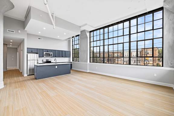 A spacious room with wooden floors and large windows.