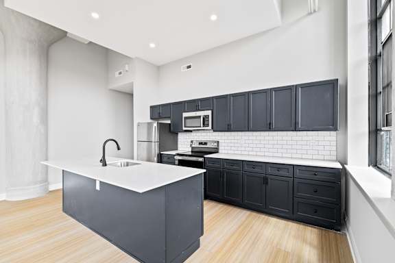 A modern kitchen with a white countertop and black cabinets.