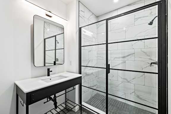 A white sink is on a black vanity with a mirror above it.