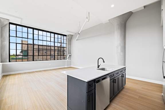 A kitchen with a large window overlooking a building.