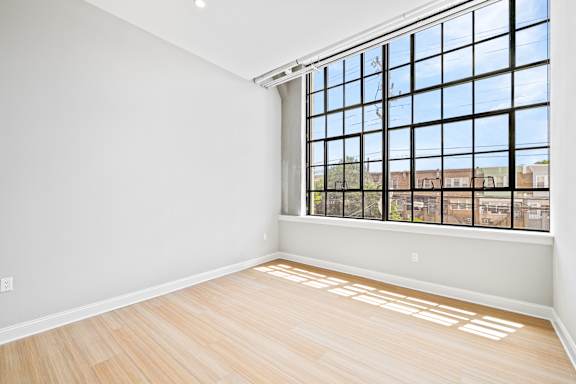 A room with a large window and wooden flooring.