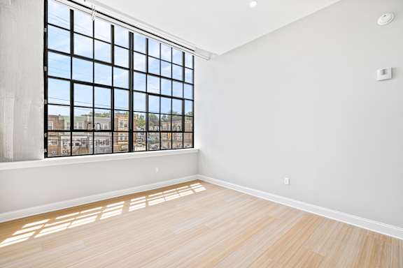 A room with a large window and wooden flooring.