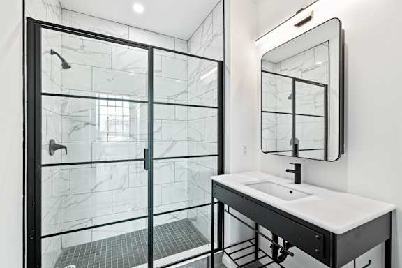 A modern bathroom with a walk-in shower and a white sink vanity.