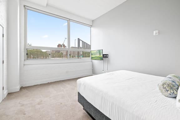 a bedroom with a bed and a large window