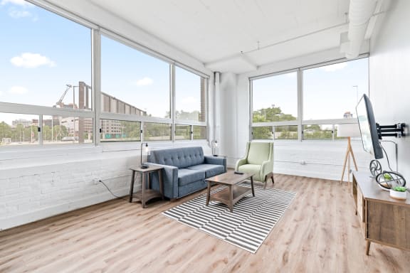 a living room with hardwood floors and large windows