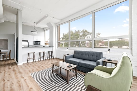 a living area with a couch coffee table chairs and a kitchen with a breakfast bar