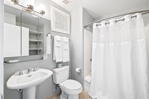 a bathroom with a white sink and toilet and a white shower curtain