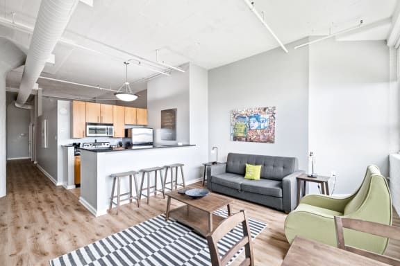 a living area with a couch coffee table and chairs and a kitchen with a breakfast bar