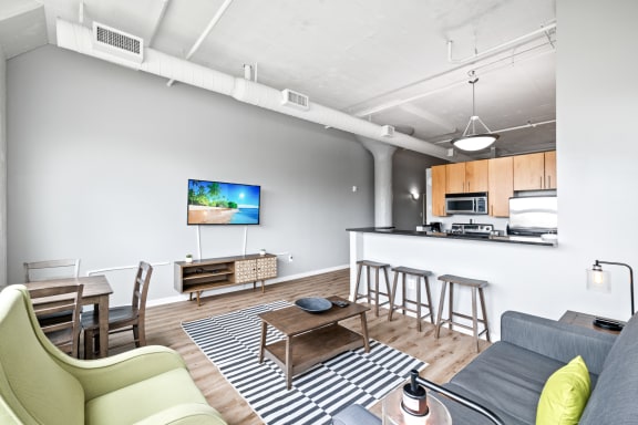 a living room with a couch a table and a chair and a kitchen with a sink and