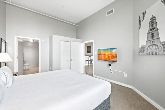 a bedroom with a large white bed and a tv on the wall