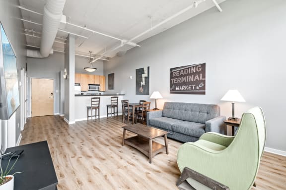 a living room with a couch a chair a table and a kitchen in the background