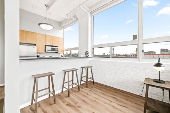 a kitchen with a bar and stools in front of a large window