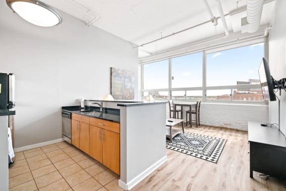 a kitchen and living room with a large window and wooden floors