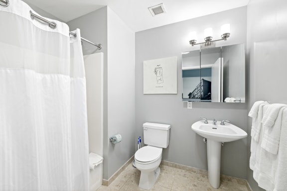 a bathroom with a white shower curtain and a white toilet next to a white sink