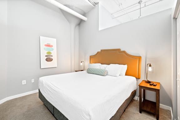 a bedroom with a large white bed and a wooden nightstand