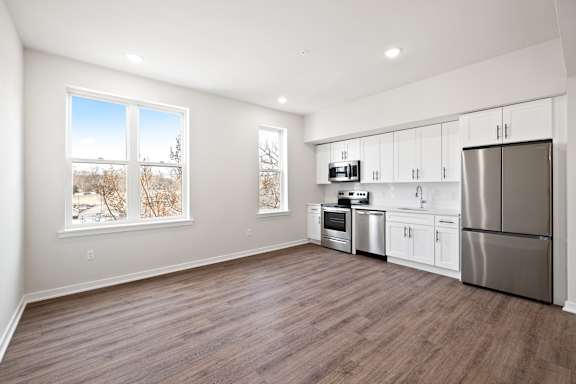 A kitchen with white cabinets and a refrigerator.