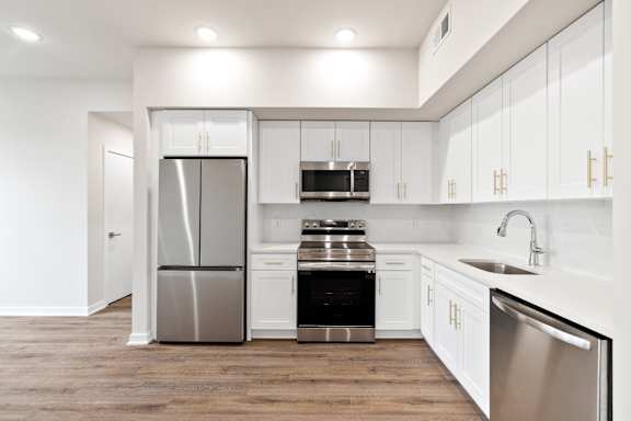 A modern kitchen with white cabinets and stainless steel appliances.