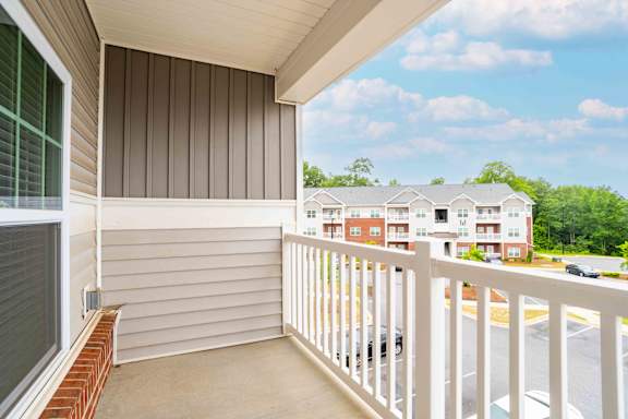 A balcony with a white railing and a view of a parking lot and buildings  at The Assembly Apartments, Greenville, 29611