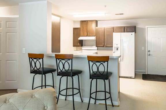 A kitchen with a white refrigerator and brown bar stools. at Bickerstaff Crossing Apartments, Henrico, VA