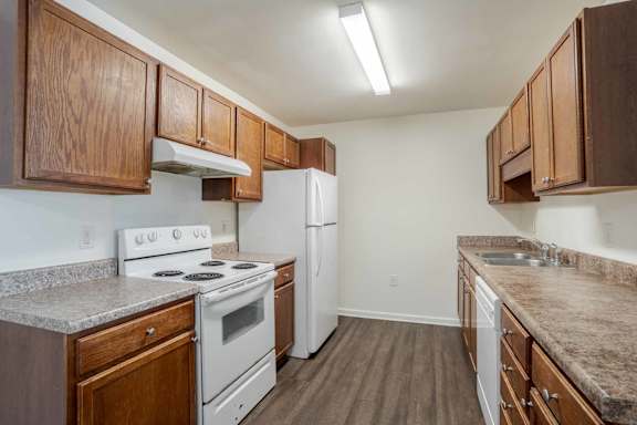 A kitchen with white appliances and wooden cabinets at Carriage Hills, Lumberton, NC 28358