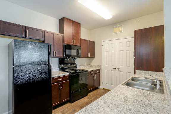 A kitchen with a black refrigerator, microwave, and stove at Cedar Terrace Apartments in Hendersonville