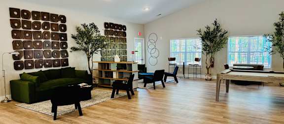 A living room with a green couch, a piano, a chair, and a table.