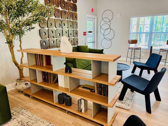 A room with a shelf, a tree, and a chair.