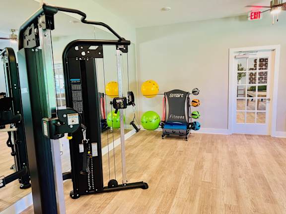 A gym with a variety of equipment including a treadmill, a stationary bike, a rowing machine, and a weight bench.