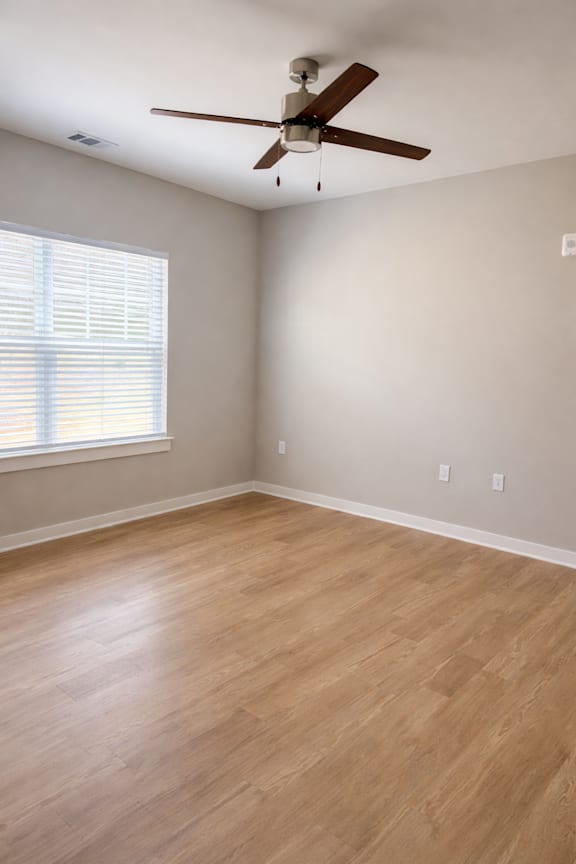 A room with a ceiling fan and wooden flooring.
