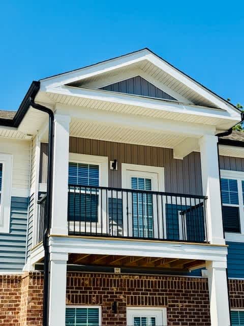 A house with a balcony and a brick wall.