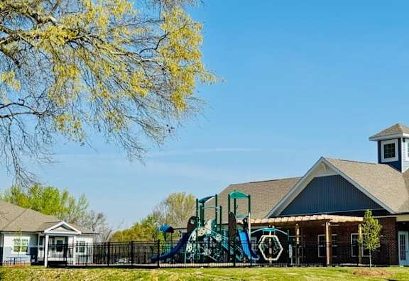 A playground with a slide and a building in the background.