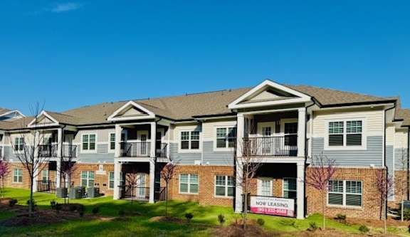 Apartment complex with a sign that says "NOW TRANSFERABLE".