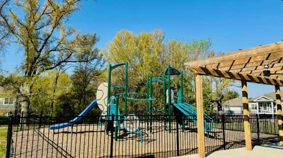 A playground with a blue slide and a green swing set.