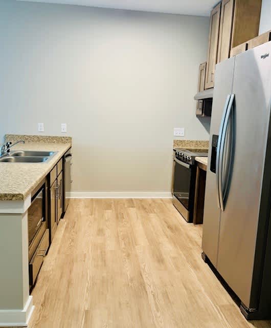 A kitchen with a refrigerator, sink, and cabinets.