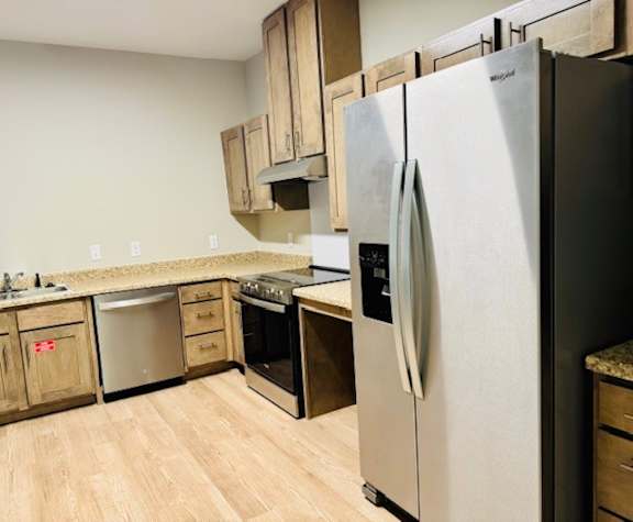 A kitchen with a stainless steel refrigerator and wooden cabinets.