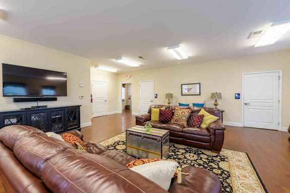 A living room with brown leather couches and a black entertainment center at Granite Falls Apartments, Rolesville, NC, 27571